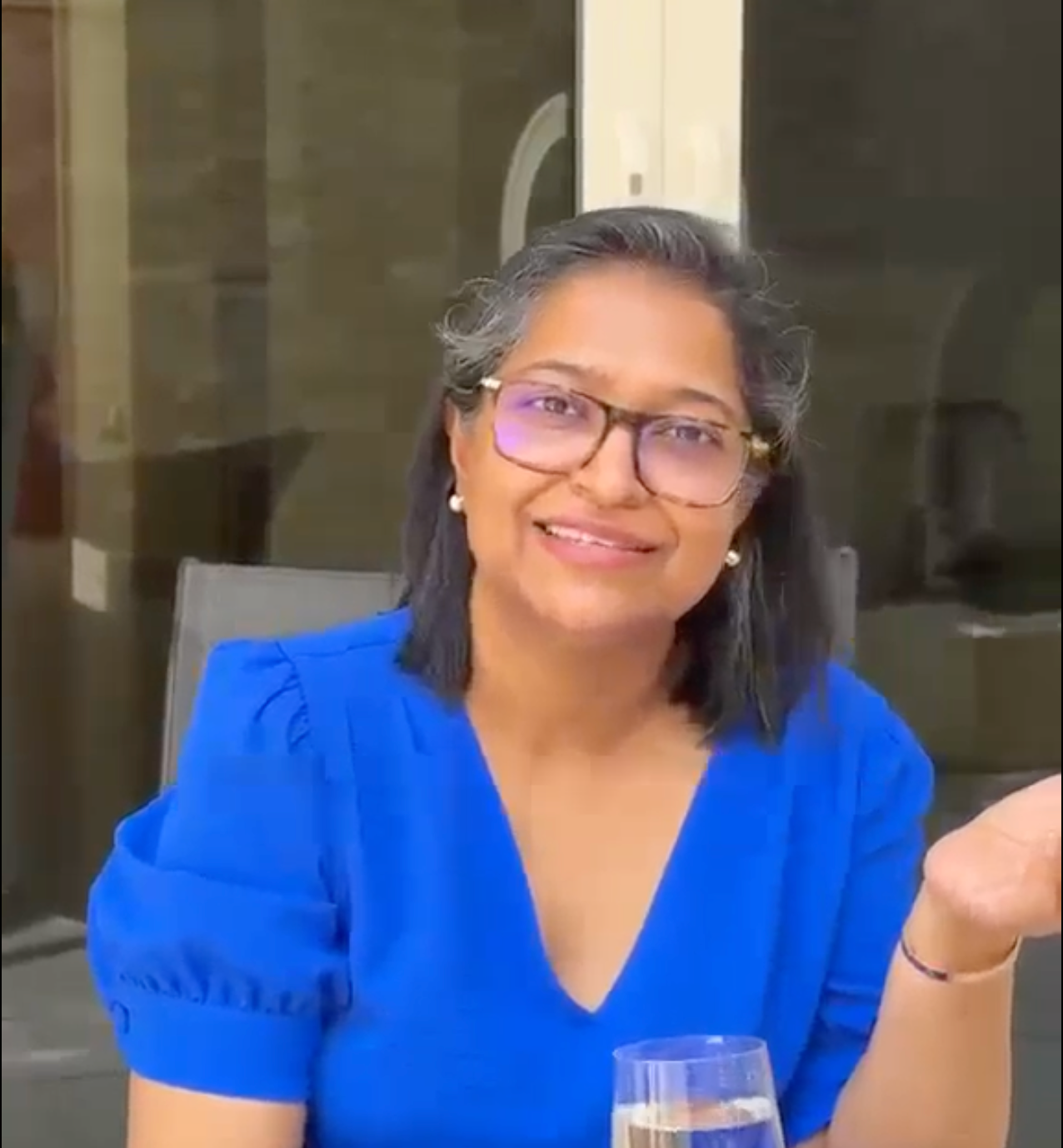 Women with glasses in a blue dress talking about her experience with Aquantis water